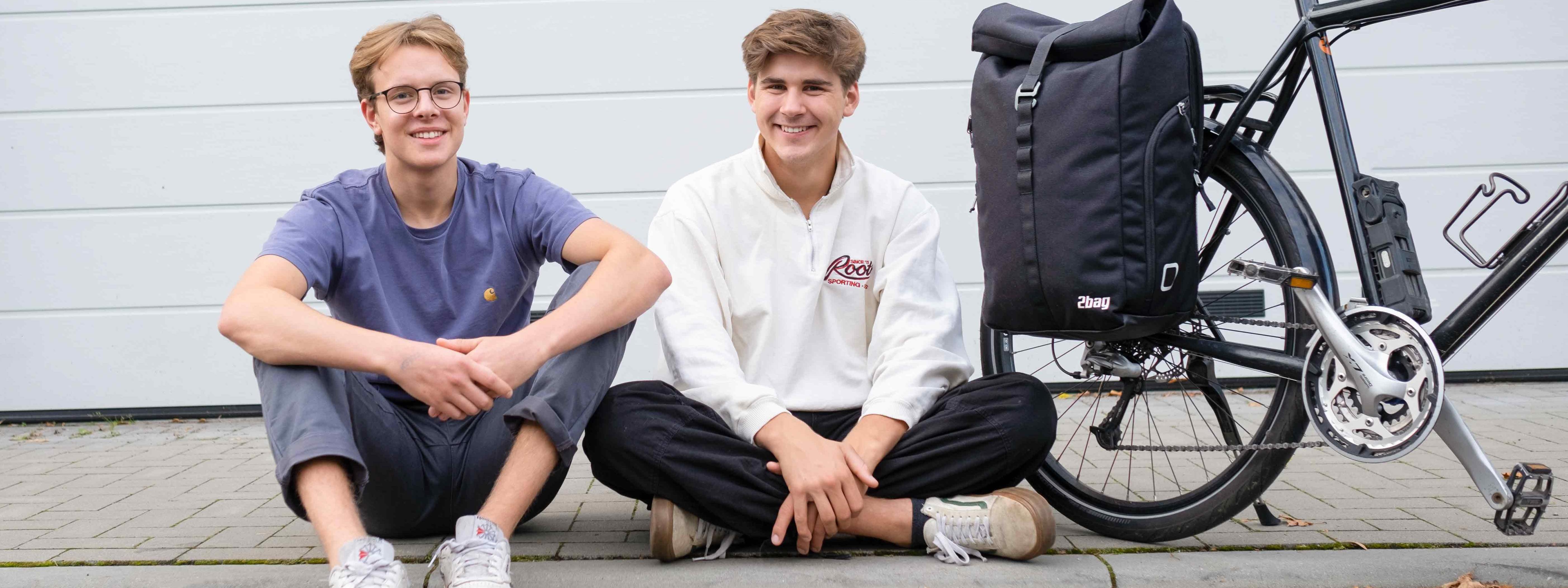 Leander Mellies and Karl Fischer from the Start-up 2bag sitting together on a sidewalk next to a bike