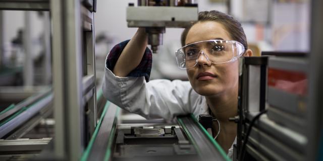 A woman is standing in front of a microscope