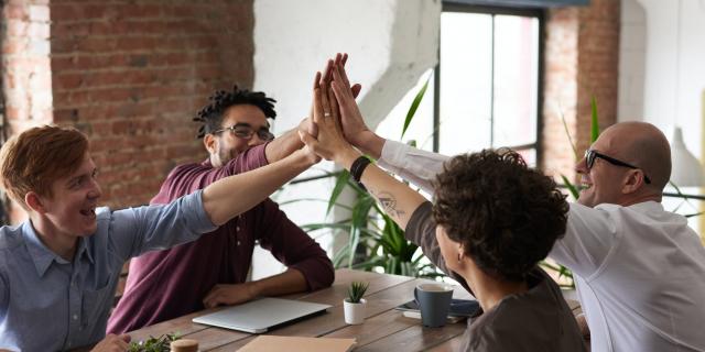 Vier Menschen geben sich ein High-Five