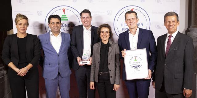 Ministerin Mona Neubauer zusammen mit Khouschnaf Ibrahim, Matthias Lohse, Hind Seiferth und Jan Knoche von der Unigy GmbH sowie Eckhard Forst, Vorstandsvorsitzender der NRW.BANK.