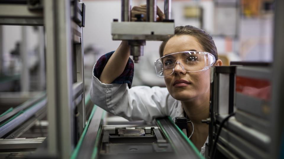 A woman is standing in front of a microscope