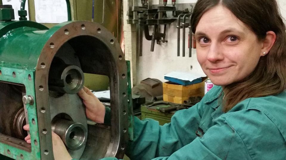 Doris Korthaus, eine junge Frau in Arbeits-Overall, arbeitet an einer Pumpe.
