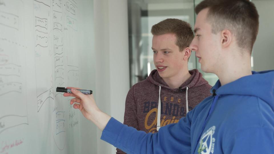 Nils Reichardt und Jonas Sander, zwei junge Männer, stehen an einem Whiteboard mit Skizze.