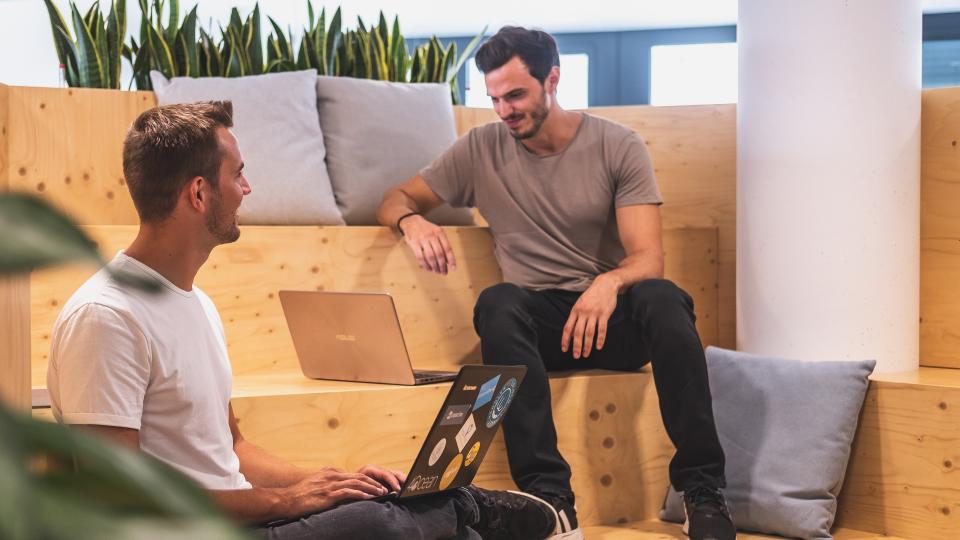 The two founders of Socialbnb sitting side by side with their laptops