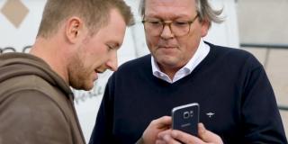 Mario Weidemann und Peter Hagedorn und schauen auf ein Smartphone.