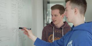 Nils Reichardt und Jonas Sander, zwei junge Männer, stehen an einem Whiteboard mit Skizze.