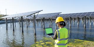 Rückansicht der Ingenieurin mit Laptop im Solarkraftwerk.