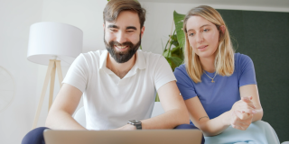 Die Gründenden von Elona Health, Alexander Braden und Johanna von Lobenstein, sitzen auf einem Sofa und schauen auf einen Laptop.