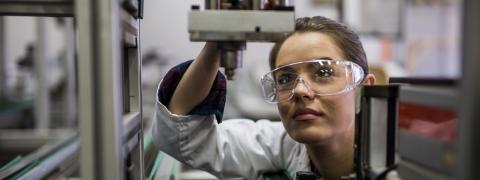 A woman is standing in front of a microscope