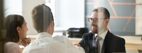 A consultant sitting in conversation with a man and a woman