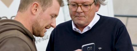 Mario Weidemann and Peter Hagedorn looking at a smartphone.
