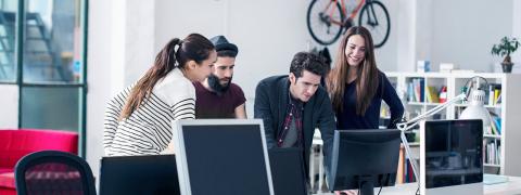 Zwei Männer und zwei Frauen in einem Star-up-Büro schauen gemeinsam auf einen Bildschirm.