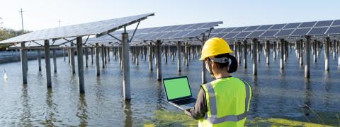 Rückansicht der Ingenieurin mit Laptop im Solarkraftwerk.