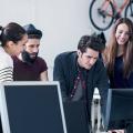 Zwei Männer und zwei Frauen in einem Star-up-Büro schauen gemeinsam auf einen Bildschirm.