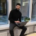 Founder Lukas Haensch is sitting on a window sill with a laptop