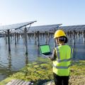 Rückansicht der Ingenieurin mit Laptop im Solarkraftwerk.