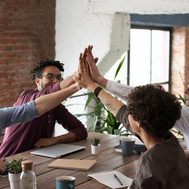 Vier Menschen geben sich ein High-Five